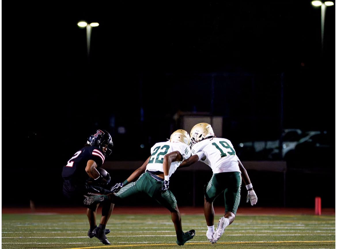 Ezra Rane Woodard number 22 closing on a ball carrier with a teammate during a night game